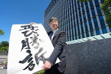 　「松橋事件」損害賠償訴訟の控訴審判決を受け、福岡高裁前で「再び勝訴」と書かれた紙を掲げる原告側の弁護士＝２７日午後