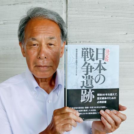 　「決定版日本の戦争遺跡」を手にする戦争遺跡保存全国ネットワーク共同代表の菊池実さん＝群馬県高崎市