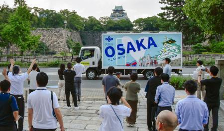 　大阪府の職員らに見送られ出発する自走式トイレカー。奥は大阪城＝２９日午後、大阪市中央区