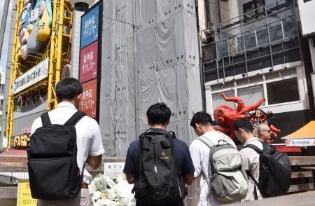 　大阪市の繁華街・道頓堀のビル火災発生から１年となり、現場付近で手を合わせる人たち＝１８日午前