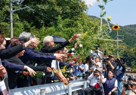　追悼集会で海に花を投げ入れる参加者＝２４日午前、京都府舞鶴市