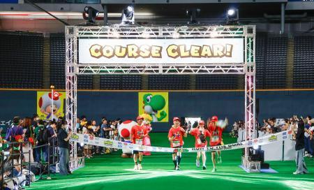 　「スーパーマリオ」の世界を表現したコースを走り、ゴールテープを切る参加者＝１３日午前、札幌市