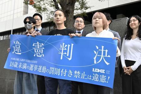 　１８歳未満の選挙運動を禁止する公選法の規定を巡る訴訟の東京地裁判決を受け「違憲判決」と記した横断幕を手にする原告ら＝２５日午後、東京地裁前