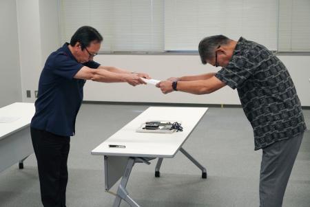 　防衛省沖縄防衛局の村井勝局長（右）に要請書を手渡す沖縄県嘉手納町の当山宏町長＝２８日午後、嘉手納町