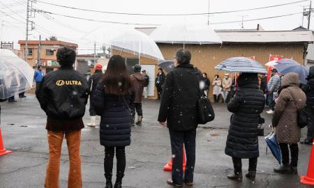　雪が降る中、候補者の街頭演説に耳を傾ける人たち＝７日午後、茨城県行方市