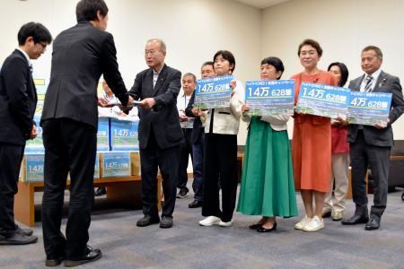 　政府側（手前）に署名を渡す議連メンバーら＝１８日午後、国会内