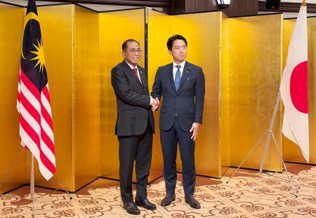 　会談前に握手するマレーシアのカレド国防相（左）と小泉防衛相＝１９日午後、東京都内