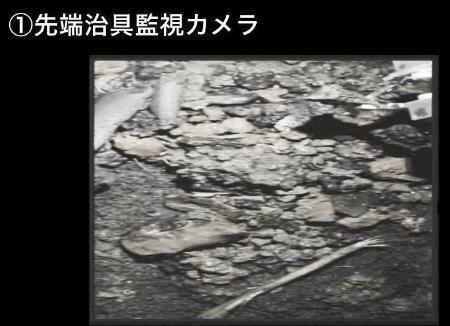 　原子炉格納容器の底部に広がる小石状のデブリの一つを爪形装置（右上）でつかんで持ち上げる様子＝９月１４日（東京電力提供）