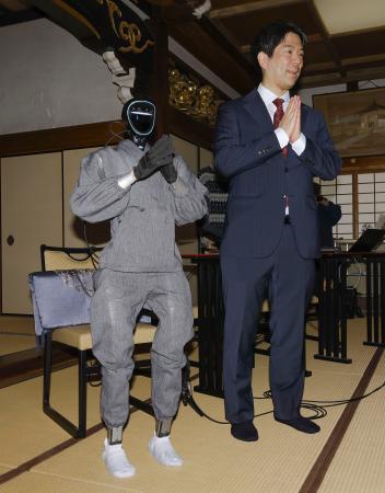 　仏教経典を学習した生成ＡＩを搭載した人型ロボット「ブッダロイド」と、開発した京都大の熊谷誠慈教授＝２４日午後、京都市東山区