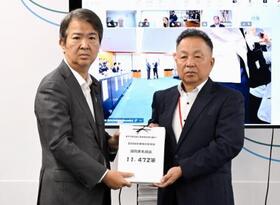 　石原環境相（左）に署名を手渡す「全国公害被害者総行動実行委員会」のメンバー＝３日午前、環境省