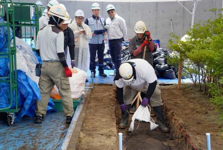 　除染土を仙台合同庁舎の植え込みに投入する作業員＝２９日午前、仙台市