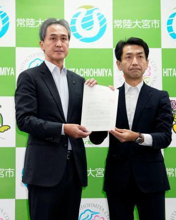 　原発の運転に伴う高レベル放射性廃棄物の最終処分場選定を巡り、経産省の担当者（右）から文献調査実施の申し入れ文書を受け取った茨城県常陸大宮市の鈴木定幸市長＝３１日午後、常陸大宮市役所