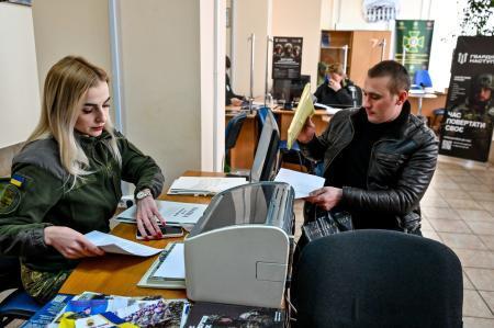　ウクライナ南部ザポロジエ州で警備隊への入隊を希望し書類に記入する男性（右）＝２０２３年２月（ゲッティ＝共同）