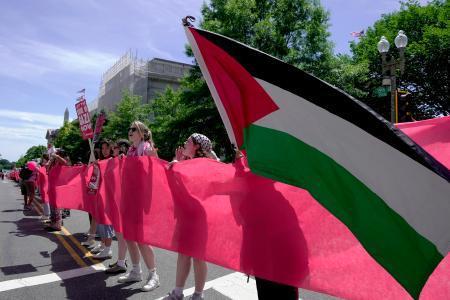 　８日、米ワシントンのホワイトハウス前で、赤い布を掲げてバイデン政権に抗議する人々（ＡＰ＝共同）