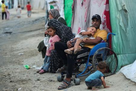 　子どもを抱える車いすのパレスチナ人＝１５日、ガザ中部デールバラハ（ロイター＝共同）