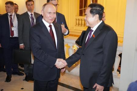 　２０日、ベトナム・ハノイでチャン・タイン・マン国会議長（右）と握手するロシアのプーチン大統領（共同）
