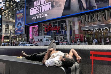 　米ニューヨークの繁華街タイムズスクエアのベンチで横になる男性＝２１日（共同）