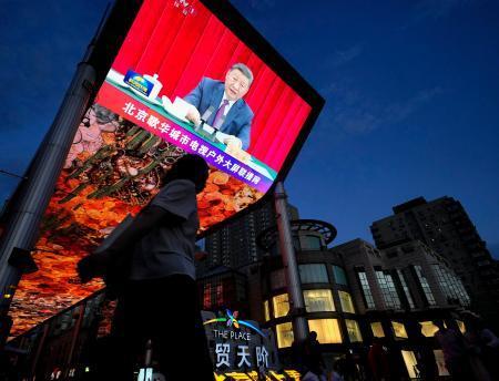 　故トウ小平氏の生誕１２０年の記念行事で演説する中国の習近平国家主席を映す大型画面＝２２日、北京（共同）