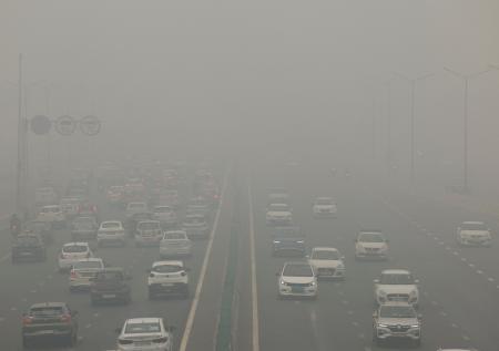 　１８日、空がスモッグで覆われたインドの首都ニューデリーの道路を走る車（ロイター＝共同）