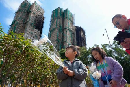 　火災があった高層住宅群の近くで花を手向ける子ども＝２５日、香港（共同）