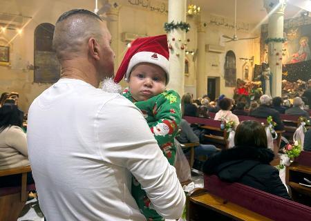 　カトリック教会で開かれたクリスマスの祝祭行事に赤ちゃんを抱いて参列する男性＝２５日、パレスチナ自治区ガザ北部ガザ市（共同）