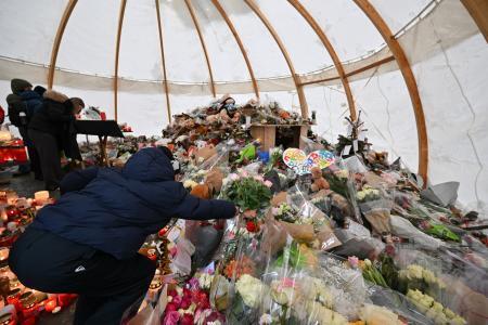 　９日、スイス南部バレー州クランモンタナで、火災の犠牲者を追悼する式典で花を手向ける参列者（ゲッティ＝共同）