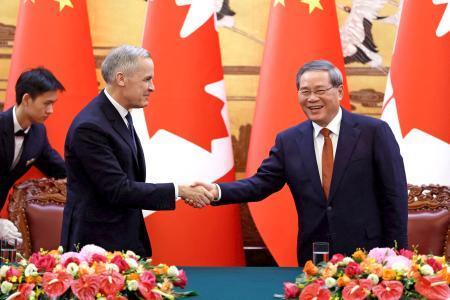 　カナダのカーニー首相（左）と握手する中国の李強首相＝１５日、北京（ロイター＝共同）