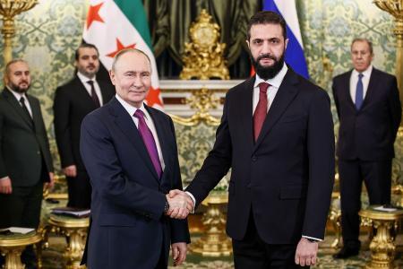 　２８日、モスクワのクレムリンで握手するロシアのプーチン大統領（左）とシリアのシャラア暫定大統領（タス＝共同）