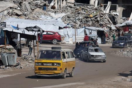 　イスラエルの攻撃で破壊された住宅のがれきの間を通るパレスチナの人々の車＝４日、ガザ市（ロイター＝共同）