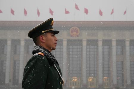 　全人代が行われる北京の人民大会堂（奥）周辺で警戒する治安当局者＝４日（共同）