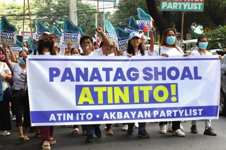 　マニラの中国大使館の関連施設前で、「スカボロー礁はわれわれのものだ」と書かれた横断幕を掲げ抗議する人たち＝２０２５年１０月（共同）