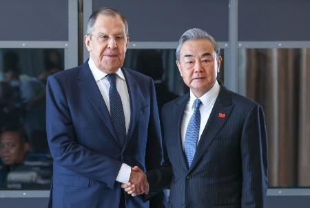 　昨年２月、南アフリカ・ヨハネスブルクでの会談で握手する中国の王毅外相（右）とロシアのラブロフ外相（タス＝共同）