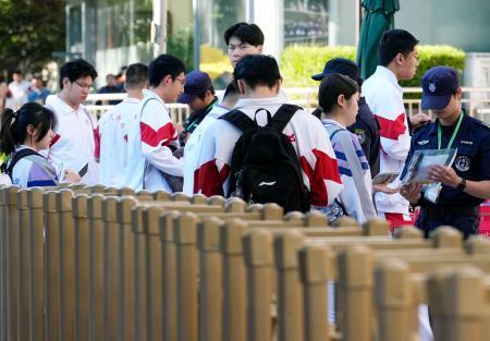 　中国の全国一斉大学入試「高考」の会場前で所持品をチェックされる学生＝７日、北京（共同）