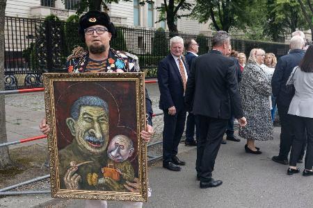 　１２日、ドイツ・ベルリンのロシア大使館前でプーチン氏の風刺画を掲げるセミョーン・スクレペツキー氏（同氏のテレグラムから・共同）