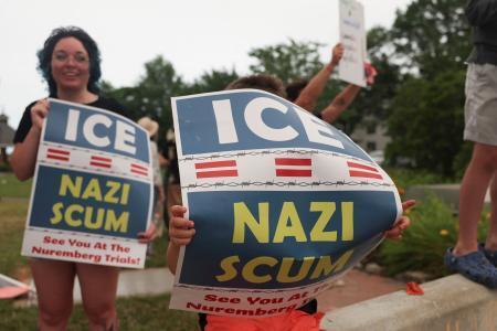 　移民・税関捜査局（ＩＣＥ）に抗議し、「ＩＣＥはナチ、クズ」とのプラカードを掲げる人たち＝１４日、メーン州ビデフォード（ロイター＝共同）