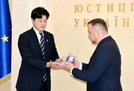 　ウクライナのマスロフ法相（右）に「ももジャン」のぬいぐるみを手渡す三谷英弘法務副大臣＝２１日、キーウ（共同）