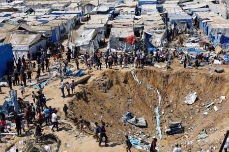 　イスラエル軍の攻撃があった医薬品の倉庫の様子を見る人たち＝１日、ガザ中部デールバラハ（ロイター＝共同）