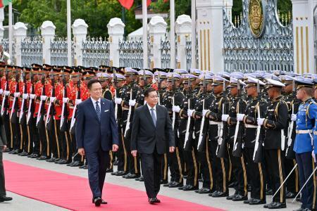 　タイ側の出迎えを受けるミャンマー親軍政権の大統領ミンアウンフライン氏（右）と並んで歩くタイのアヌティン首相＝＝６日、バンコク（共同）