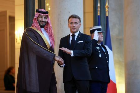 　サウジアラビアのムハンマド皇太子（左）と握手するフランスのマクロン大統領＝２４日、パリ（ロイター＝共同）