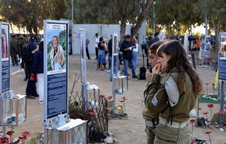 　イスラム組織ハマスが奇襲した野外音楽フェスティバルの会場で犠牲者の追悼パネルを見る女性ら＝７日、イスラエル南部レイム（共同）