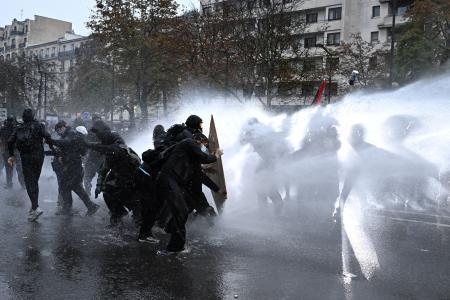 　フランス・パリでの抗議デモで、警官隊から放水を受ける参加者ら＝２４日（ロイター＝共同）