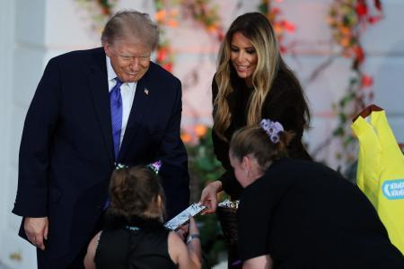 　子どもたちにお菓子を配るトランプ米大統領夫妻＝２９日、ワシントン・ホワイトハウス（ロイター＝共同）