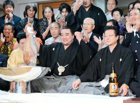 　伊勢ケ浜親方（右手前）の隣で力強く鯛を持ち上げる日馬富士（中央）