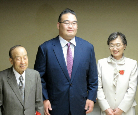 　整髪を終え、父・元昭さんと母・寿子さんに挟まれ撮影に応じる振分親方（中央）