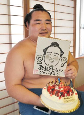 　２９歳の誕生日を迎えた鶴竜は報道陣から贈られたケーキと似顔絵を手に笑顔