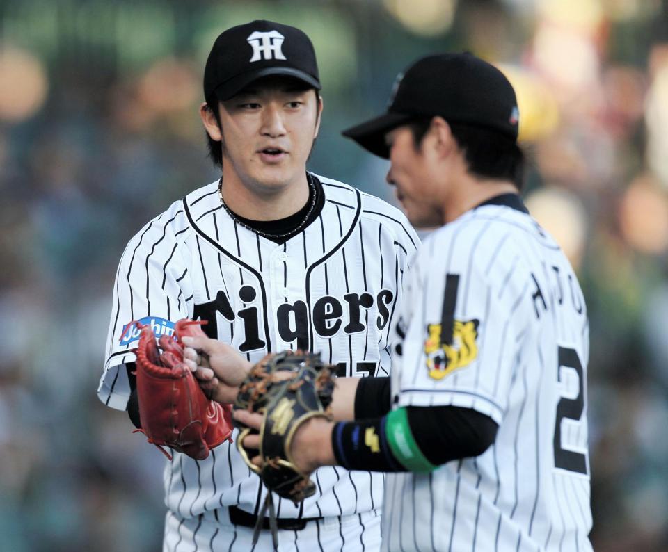 １回を３人でピシャリと抑え、阪神・北條史也（右）とタッチを交わす阪神・岩貞祐太＝甲子園球場（撮影・北村雅宏）
