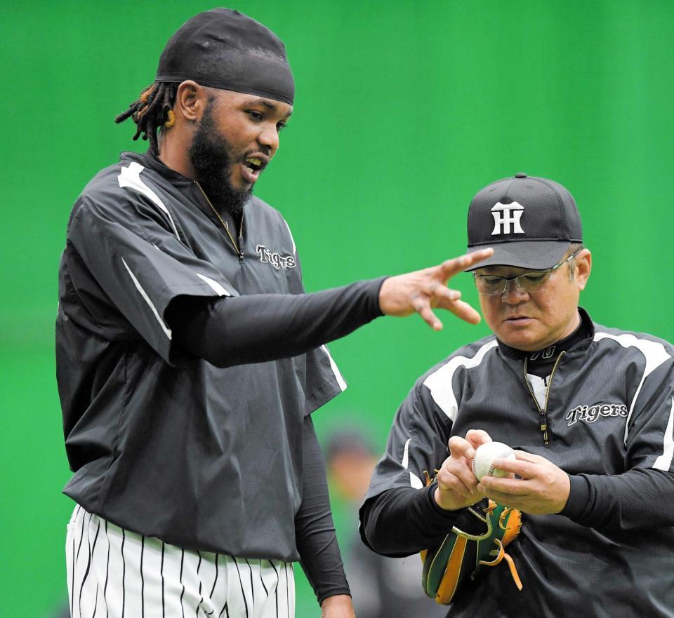 　高代コーチ（右）から変化球の握りを教えてもらうドリス