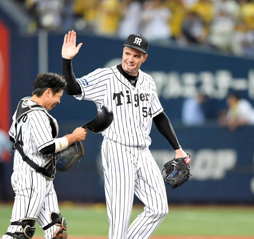 　完封で１１勝目を挙げ、梅野の頭を笑顔ではたくメッセンジャー