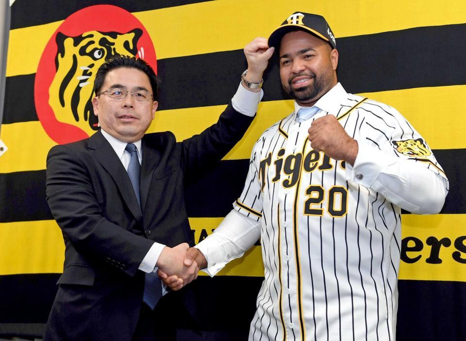 　入団会見でロサリオと握手をかわす谷本球団本部長