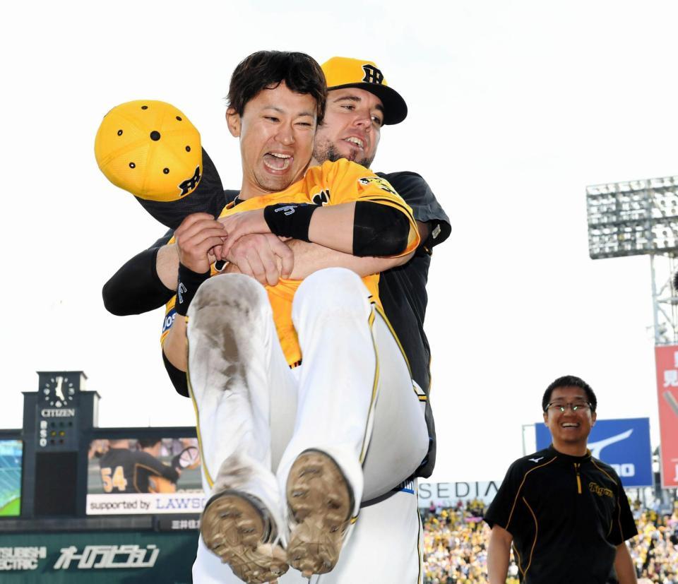 試合後、阪神・メッセンジャーに抱きかかえられ笑顔を見せる阪神・上本＝甲子園（撮影・田中太一）